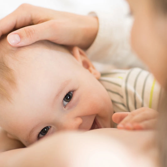 Photo of a toddler breastfeeding and smiling 